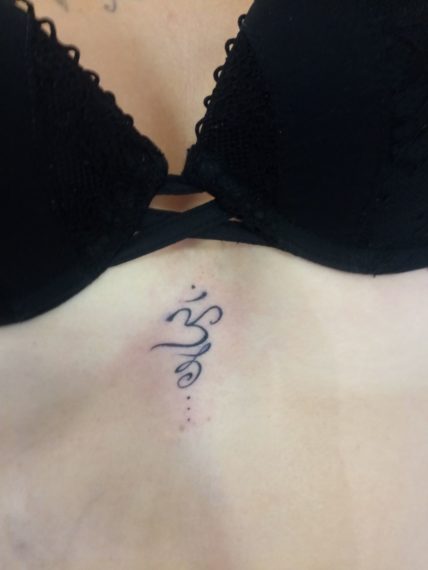 tatouage Om entre les seins par lily Tarawa Cap d'Agde